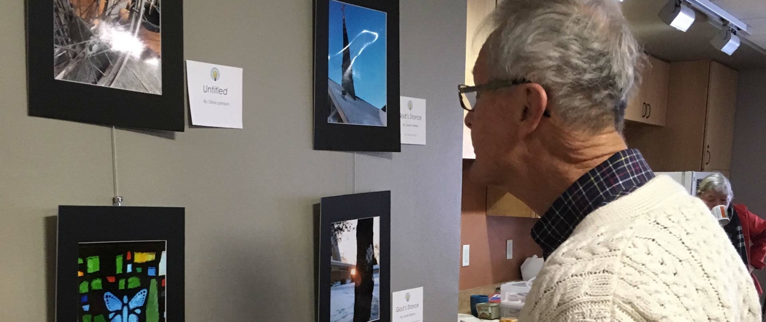 Man looking at photos of various arts integration projects arranged on a wall